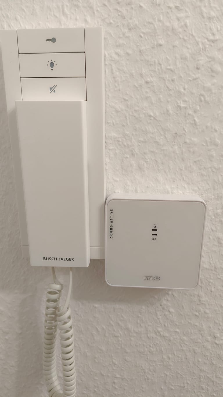 Eine Busch-Jaeger-Sprechstelle an der Wand mit einem weißen m-e-Sound-Active-Kästchen darüber.