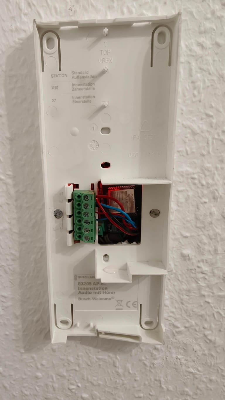 The ESP32 board sitting inside the cable box behind the Busch-Jaeger 83205 wall casing.