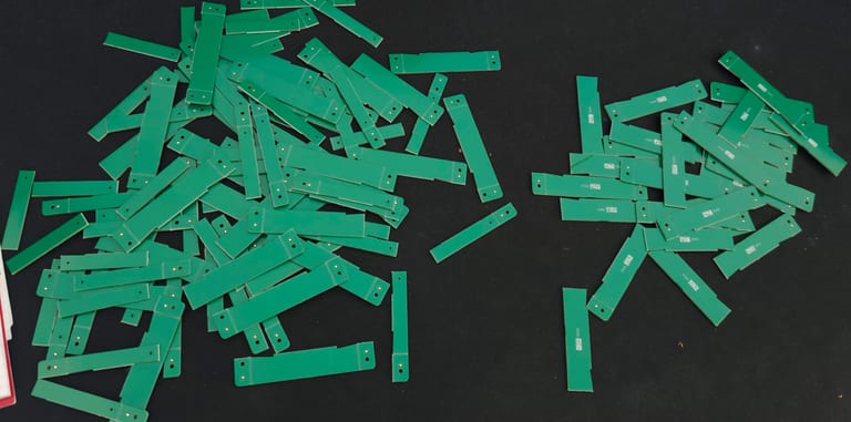 A large pile of green PCB break-off rails left over after separating 30 boards.